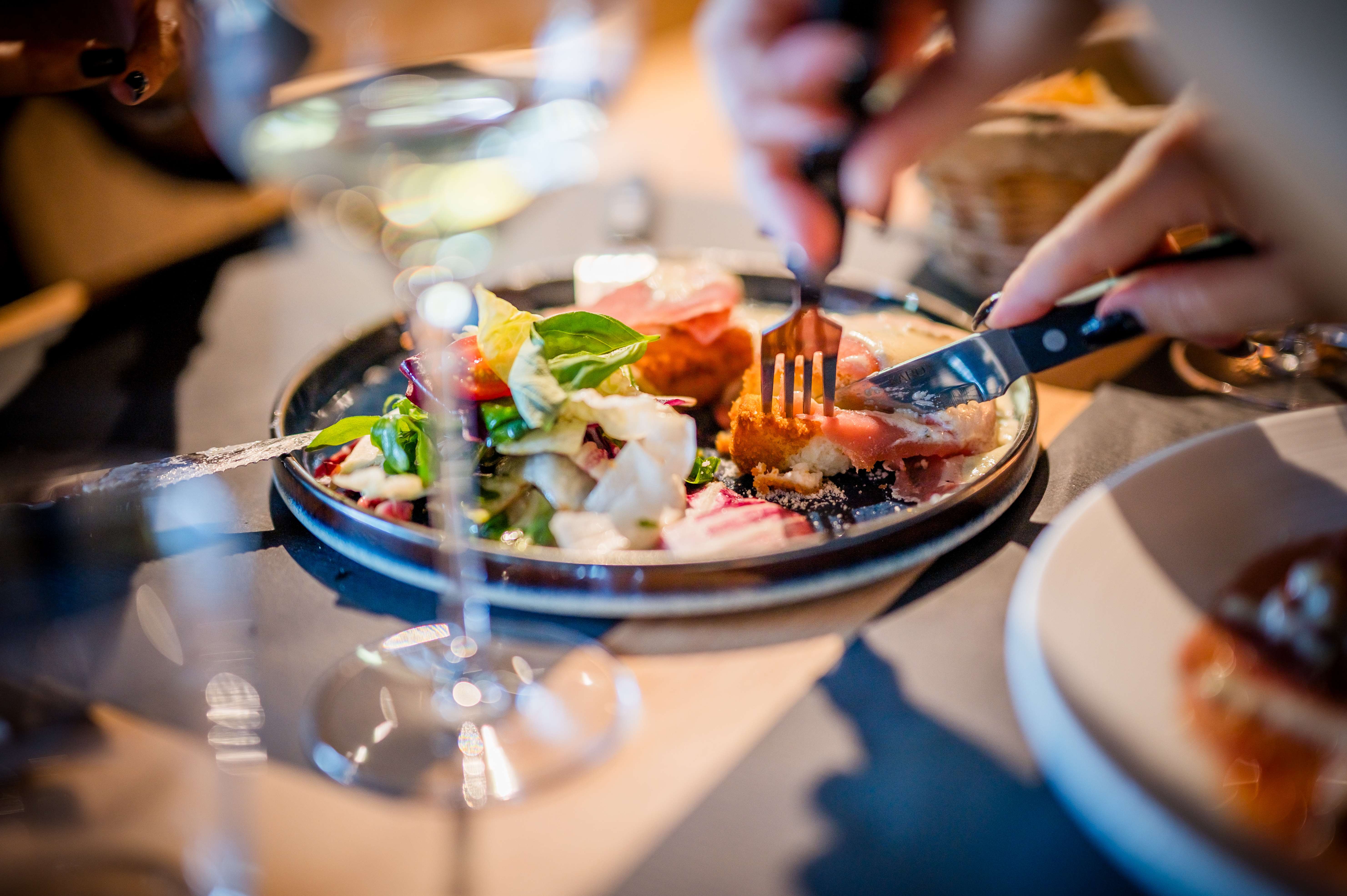 Salade italienne avec burrata, jambon de Parme, tomates cerises et basilic dégustée à table